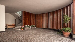 Um espaço amplo e interno, com piso de tijolos, painéis de madeira e plantas em vasos.
