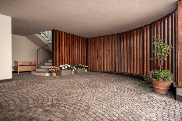 Un vaste espace intérieur doté d’un sol en briques, de murs lambrissés, d’un escalier et de plantes en pot.