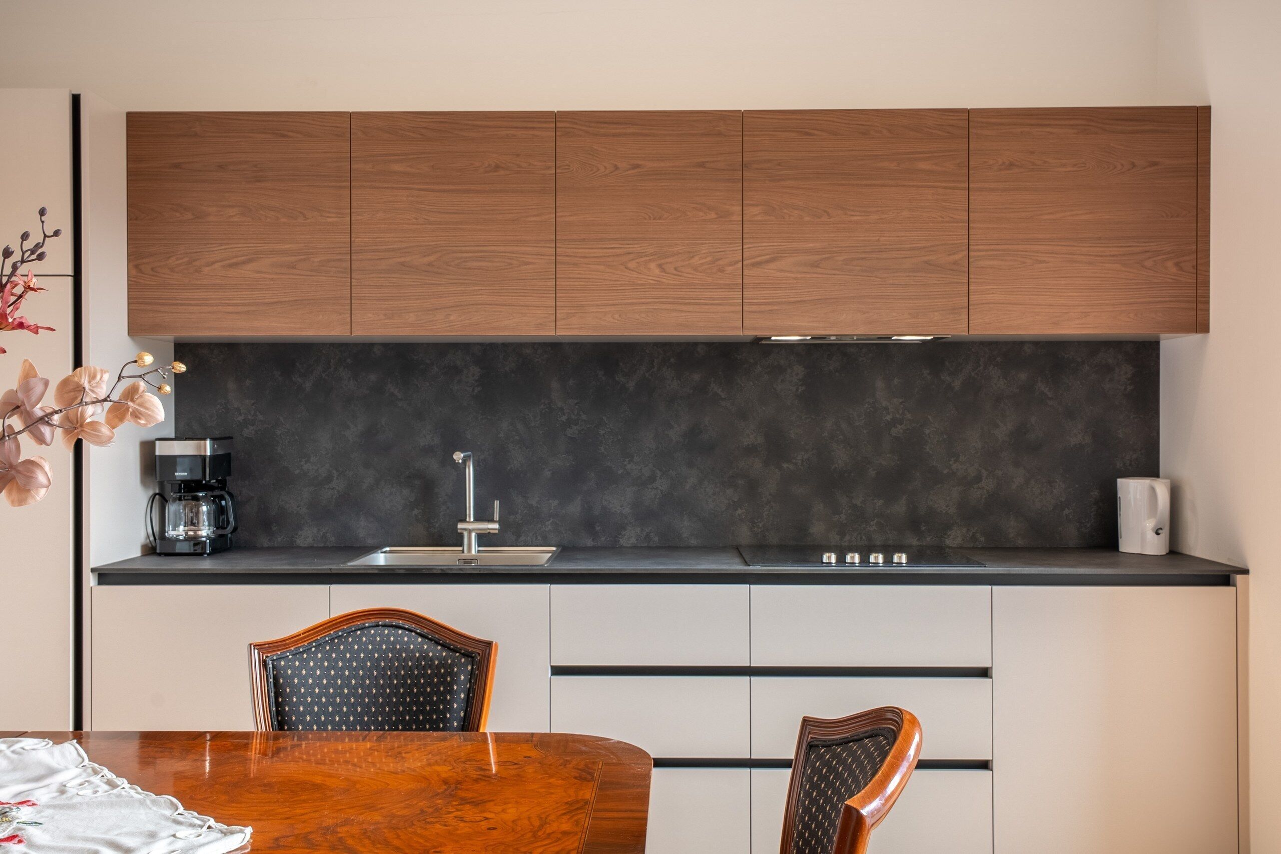 Eine moderne Küche mit Holzschränken, einer schwarzen Arbeitsplatte und einem Essbereich mit Holztisch und Stühlen.