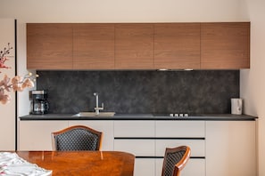 Una cocina moderna con armarios de madera, encimera negra y una zona de comedor con mesa y sillas de madera.