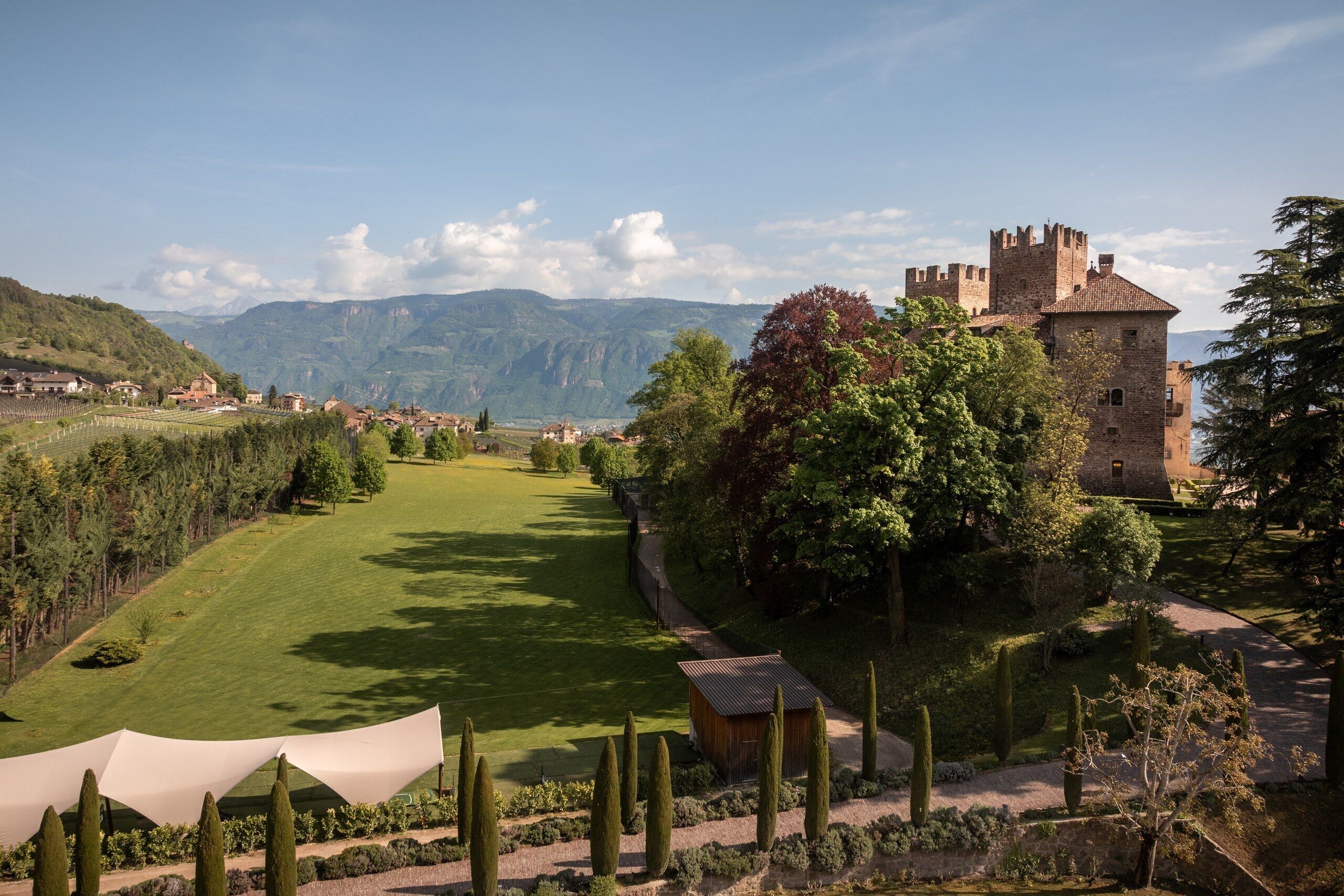 Un château avec une pelouse bien entretenue et un petit bâtiment en premier plan.