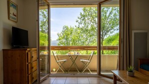 A balcony with a table and chairs, a television on a cabinet, and a poster on the wall.