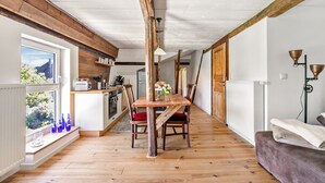 Comedor con suelo de madera, una mesa y sillas, un ventanal con vistas y un radiador en la pared.
