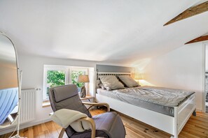 A bedroom with a bed, a chair, a lamp, and a window. - Apartment Klein Bullerbü in Schülp an der Nord Sea with Shared Terrace, Garden and Wi-Fi (Schülp)