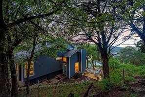 A modern house with a deck, surrounded by trees. - Fully Renovated Lakeside Home - Boat Dock, Firepit, Gorgeous Views! (Lago Vista)