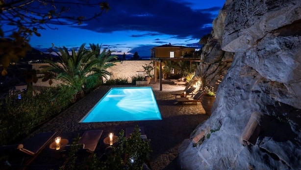 Ein Swimmingpool mit Liegestühlen und einer Steinmauer.