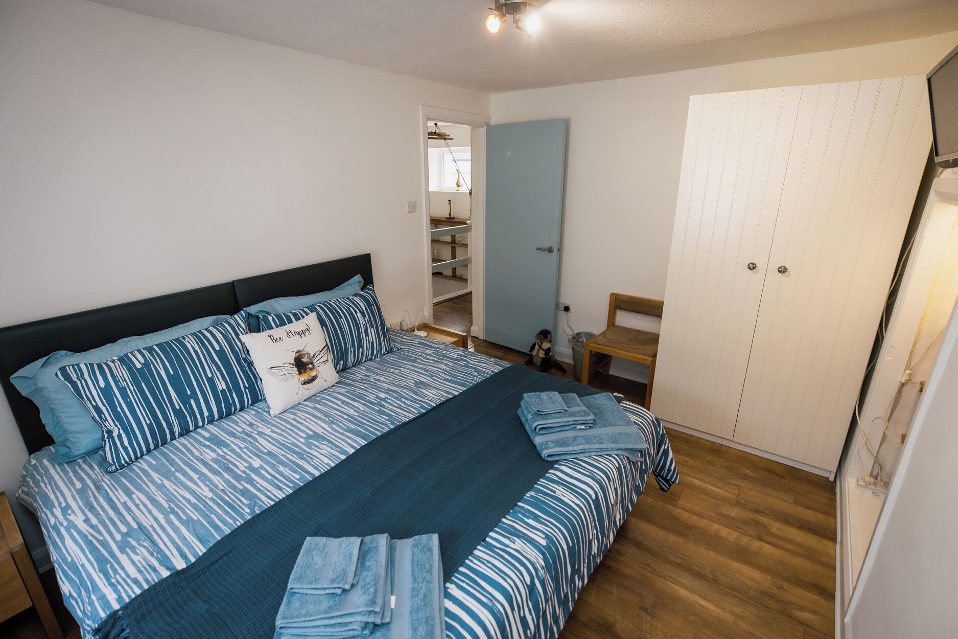 A bedroom with a bed, a wardrobe, a desk, and a chair.