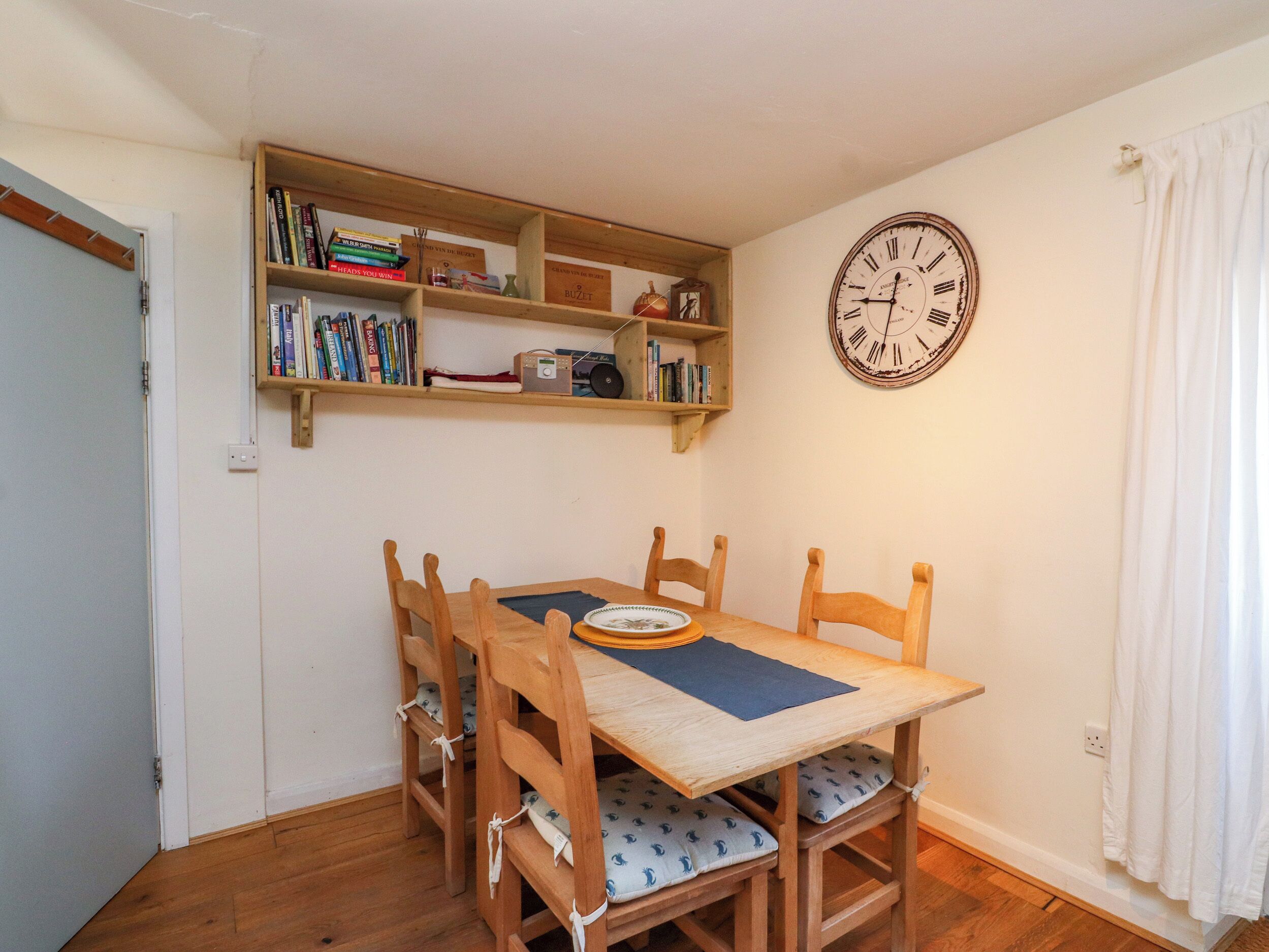Un comedor con una mesa de madera, sillas, un reloj y estanterías.