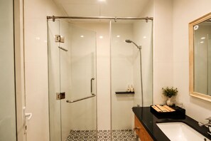 Une salle de bain moderne avec une douche à parois de verre, un plan de toilette noir et un lavabo blanc.