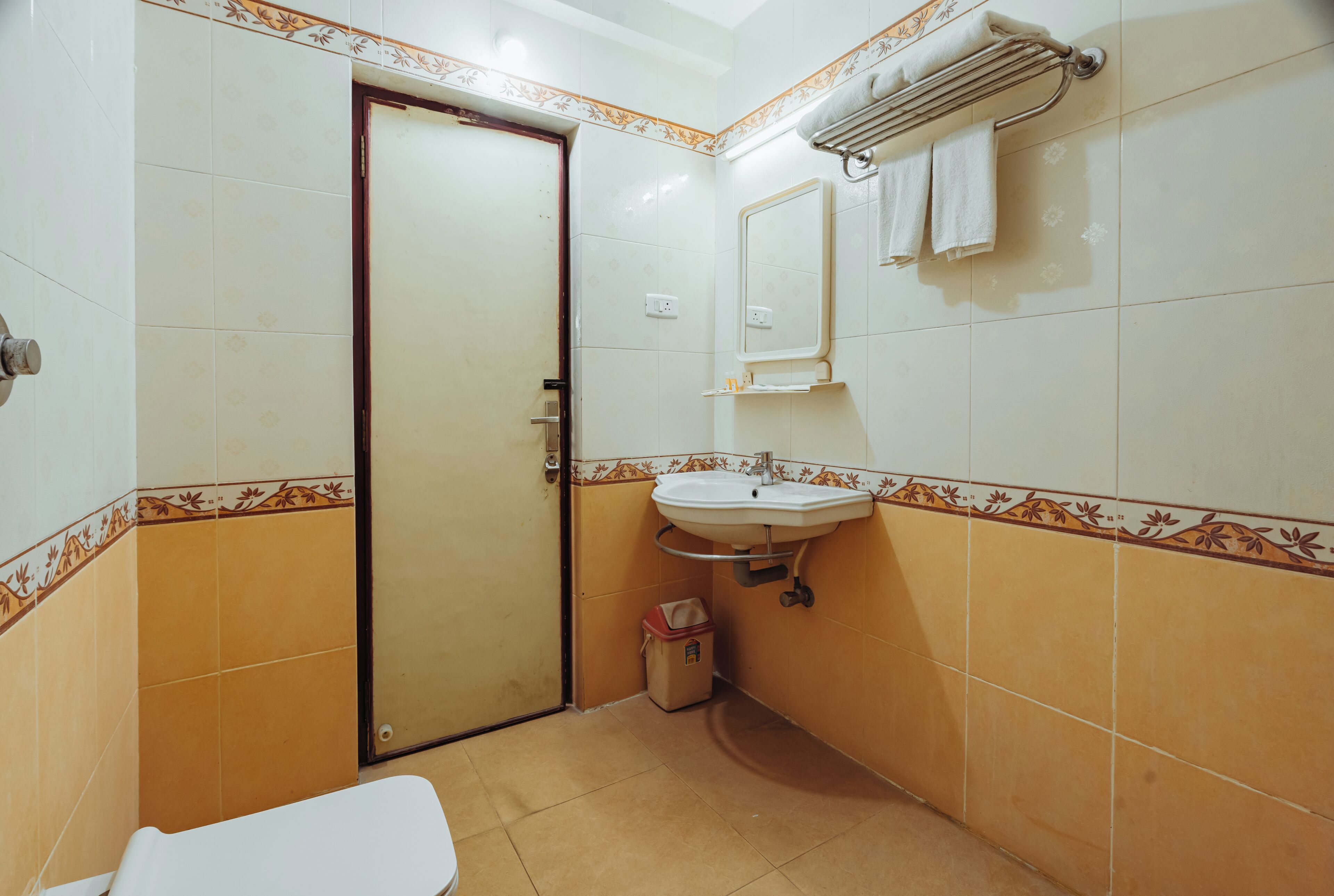A compact bathroom with a toilet, sink, and a small trash bin.