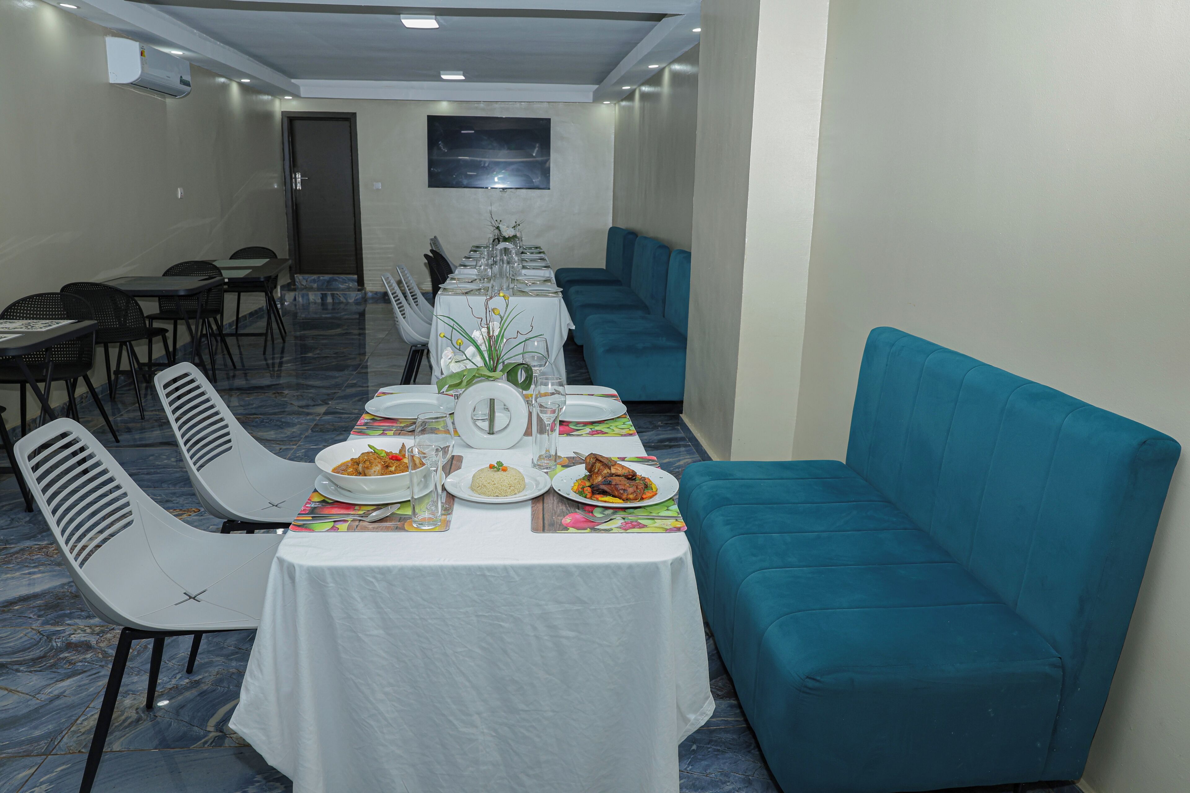 Un coin repas avec une longue table dressée pour le repas, des chaises et un canapé bleu.
