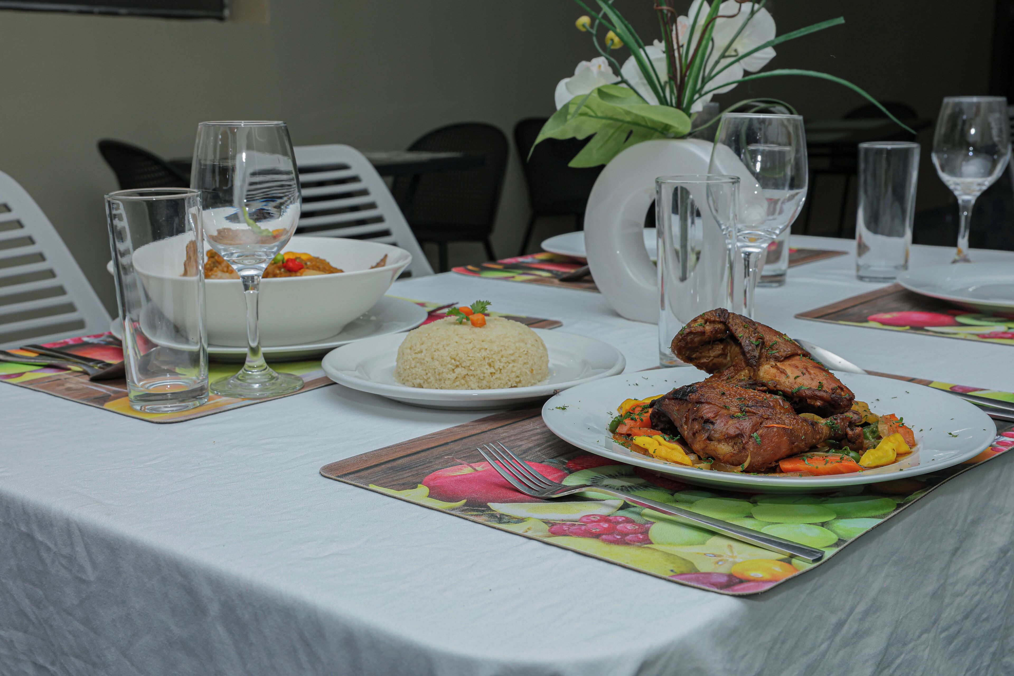 Uma mesa de jantar posta com pratos de comida, copos e talheres.