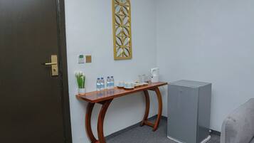 Um quarto com uma mesa de madeira, um refrigerador, um ornamento de parede e uma porta.
