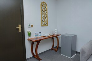 Una habitación con una mesa de madera, un refrigerador, un adorno en la pared y una puerta.