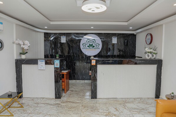 A hotel reception desk with a marble floor, a wooden stool, and a sign indicating hotel services.