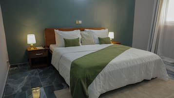 A hotel room with a bed, two bedside tables with lamps, a nightstand, a wall socket, and a window with curtains.