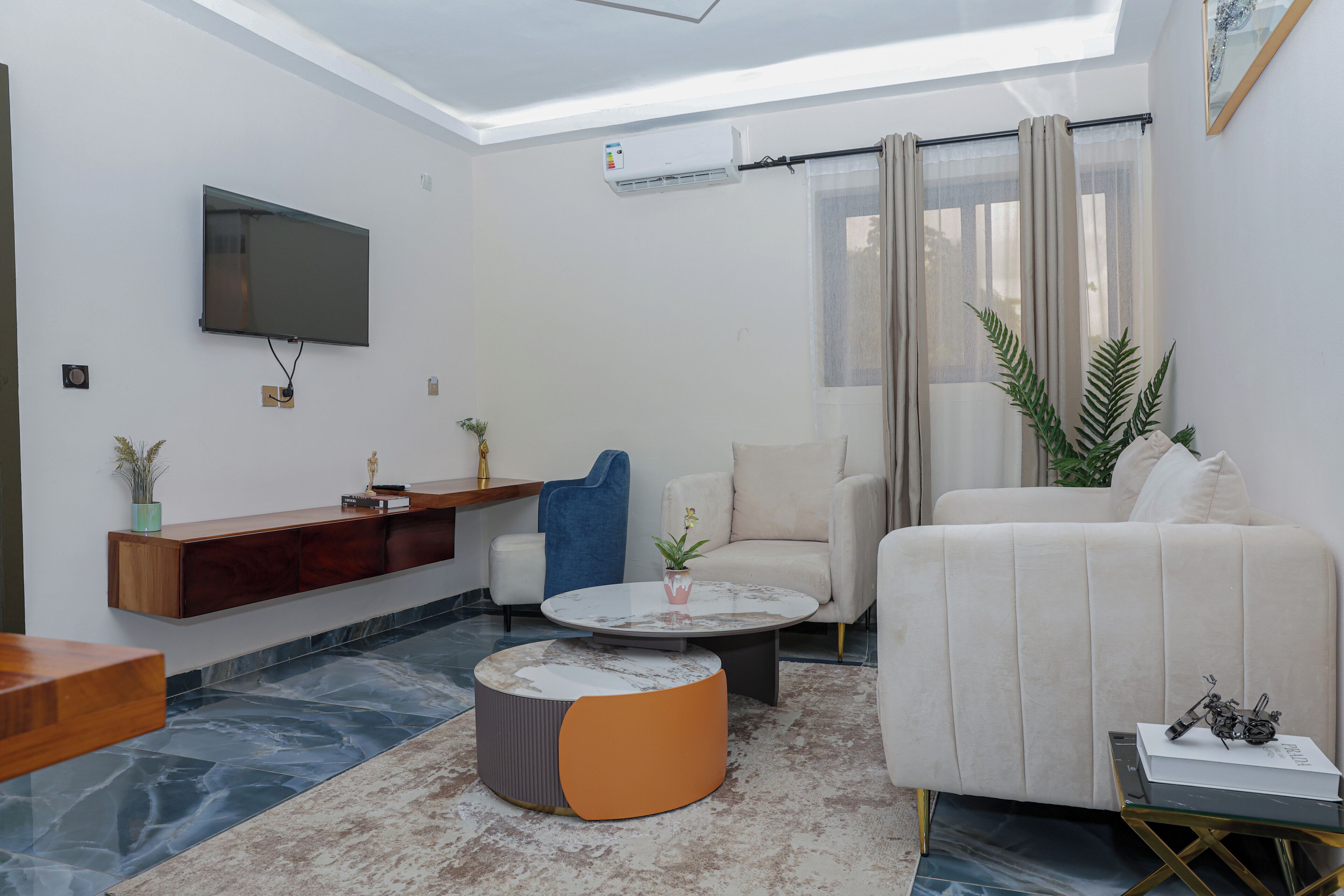 A modern living room with a flat-screen TV mounted on the wall, a sofa, a coffee table, and a small side table.