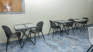 A room with a marble floor, several tables and chairs, and a window with a reflection. - Les jardins d'Adzopé (Adzope)