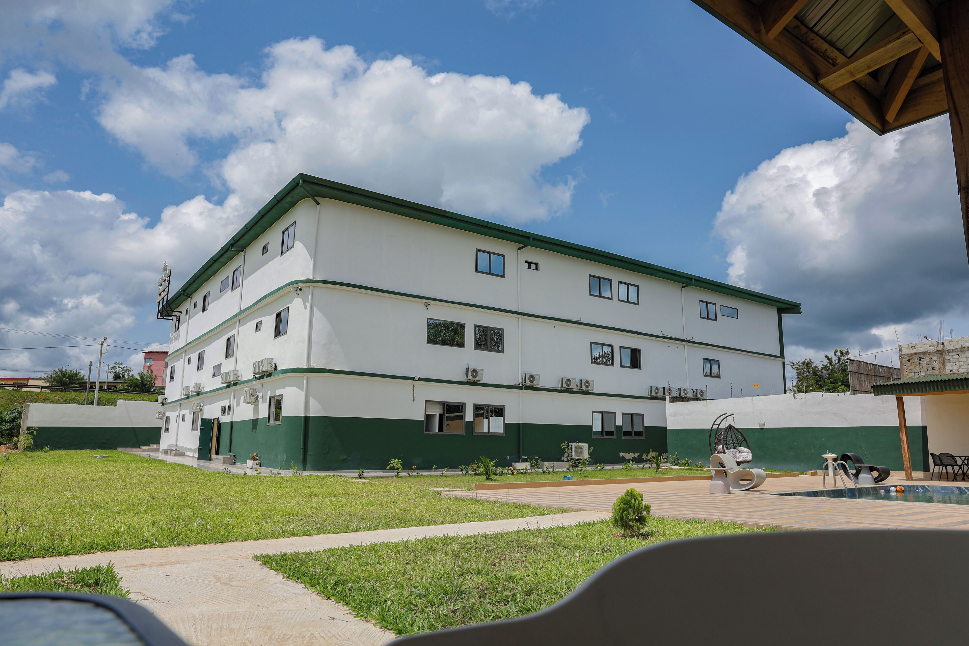 Um edifício de vários andares com telhado plano e esquema de cores verde e branco.