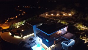 Ein modernes Haus mit Swimmingpool, Sitzgelegenheiten im Freien und einer gut beleuchteten Terrasse.