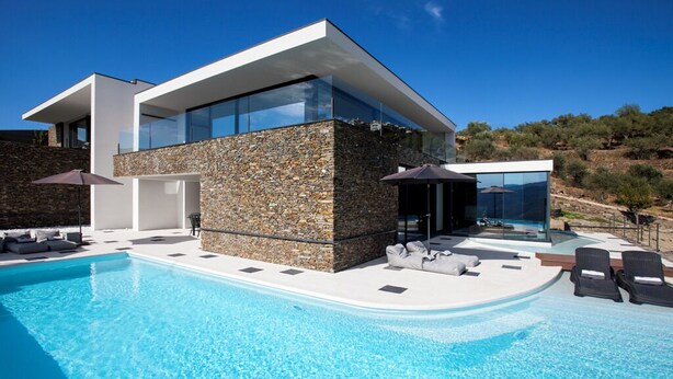 Ein modernes Haus mit Swimmingpool, Naturstein-Fassade und Glasfenstern.