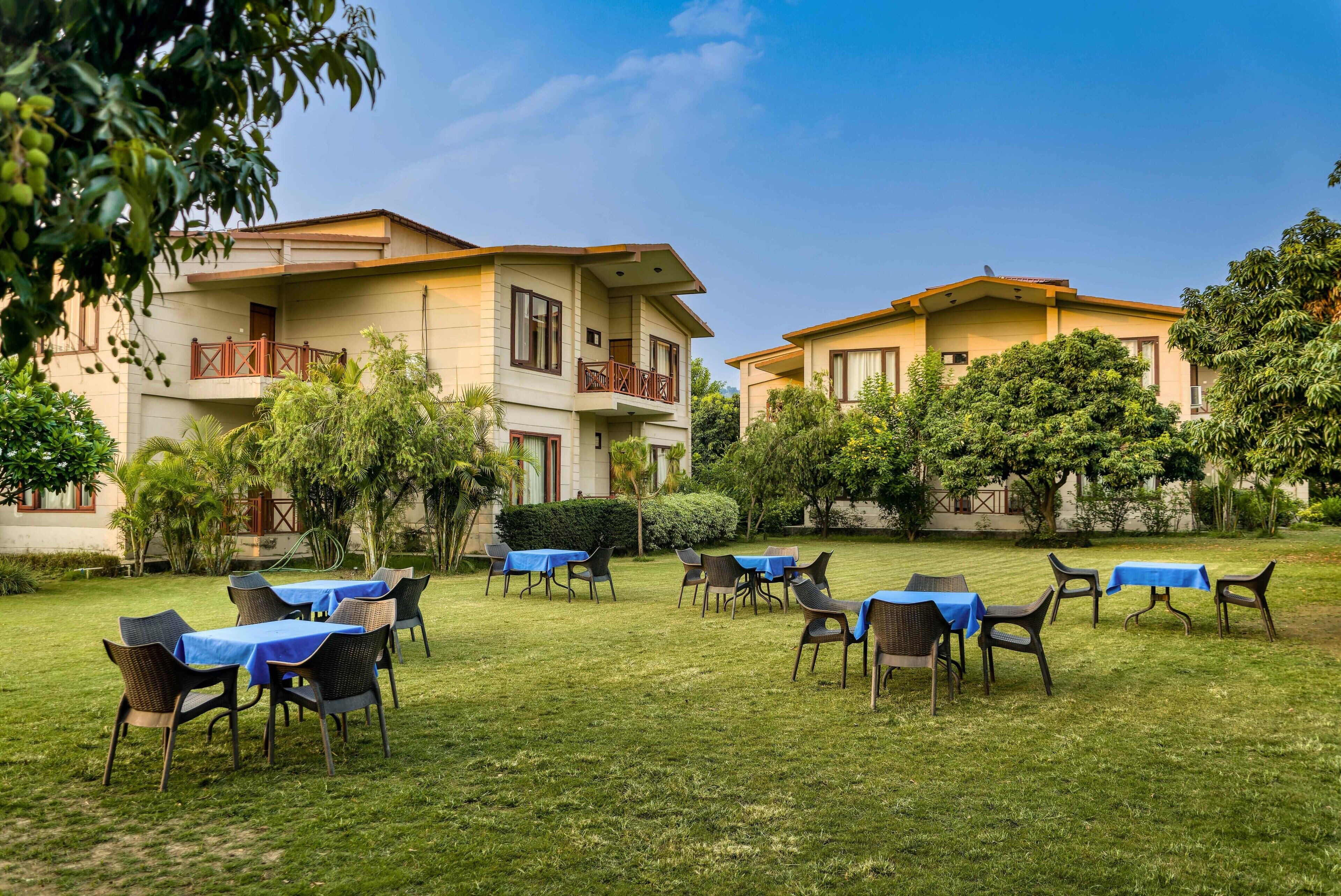 A hotel courtyard with outdoor seating, a pool, and a building with balconies.