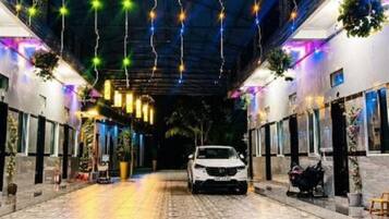 Un paseo techado con luces colgantes, un coche estacionado en el centro y macetas con plantas a lo largo de los lados.
