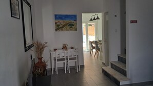 A hallway with a dining area, a staircase, and a painting on the wall.