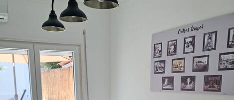 Een eetruimte met een tafel gedekt voor vier personen, stoelen, een muur met ingelijste foto’s en een uitzicht door een glazen deur.