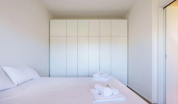 Une chambre d’hôtel comprenant un lit, une armoire et un ensemble de serviettes.