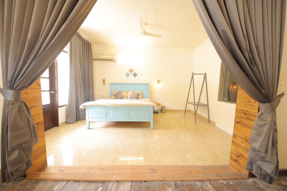 Une chambre à coucher avec un lit, des rideaux, un ventilateur de plafond et un plancher en bois.