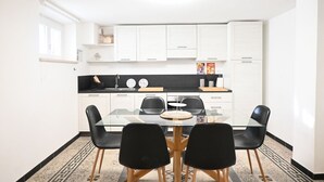Una cocina moderna con gabinetes blancos, una mesa de comedor de vidrio y sillas negras.