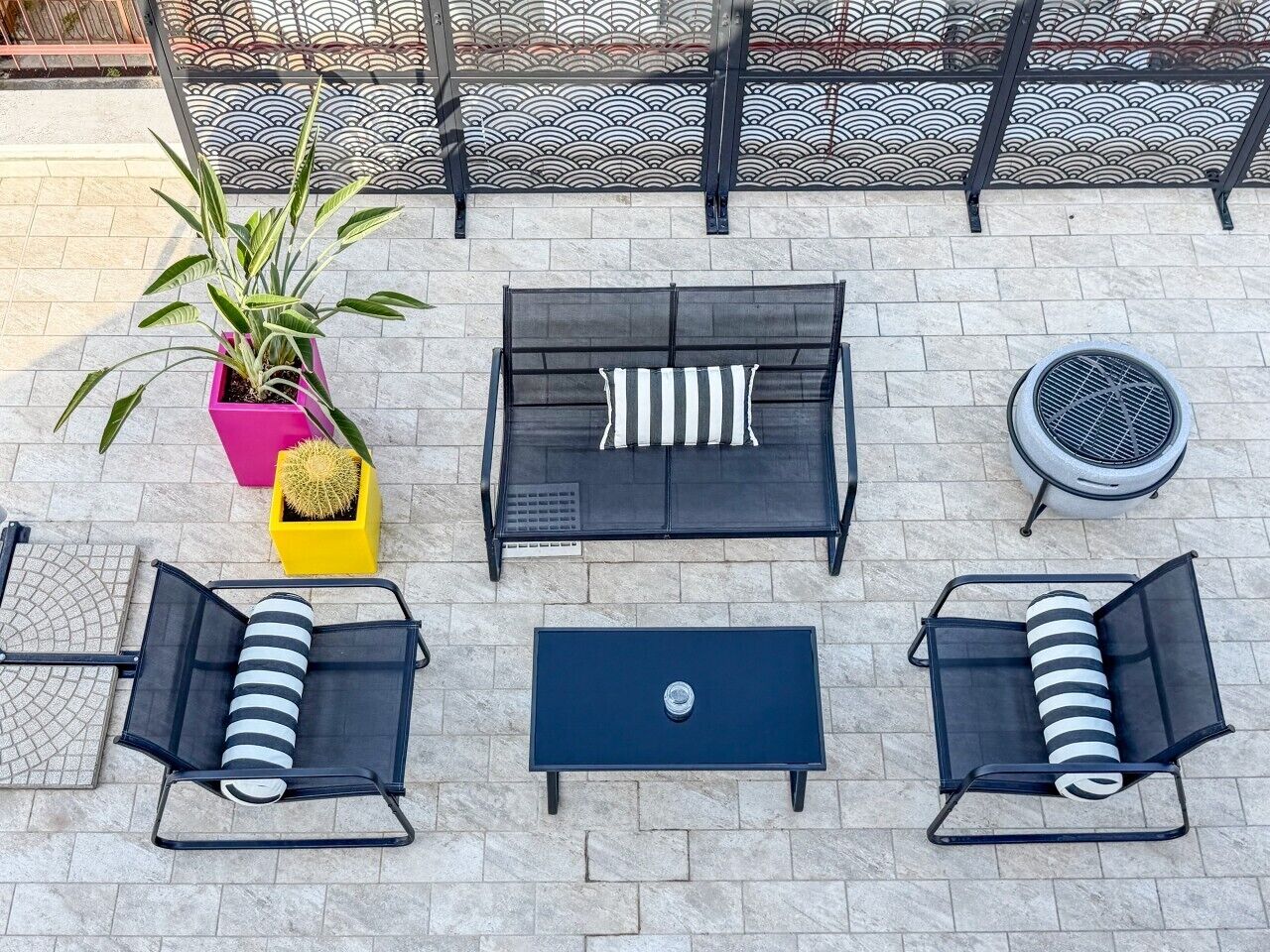 An outdoor seating area with a sofa, two armchairs, a coffee table, and a potted plant.