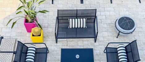 An outdoor seating area with a sofa, two armchairs, a coffee table, and a potted plant.