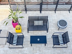 An outdoor seating area with a sofa, two armchairs, a coffee table, and a potted plant.