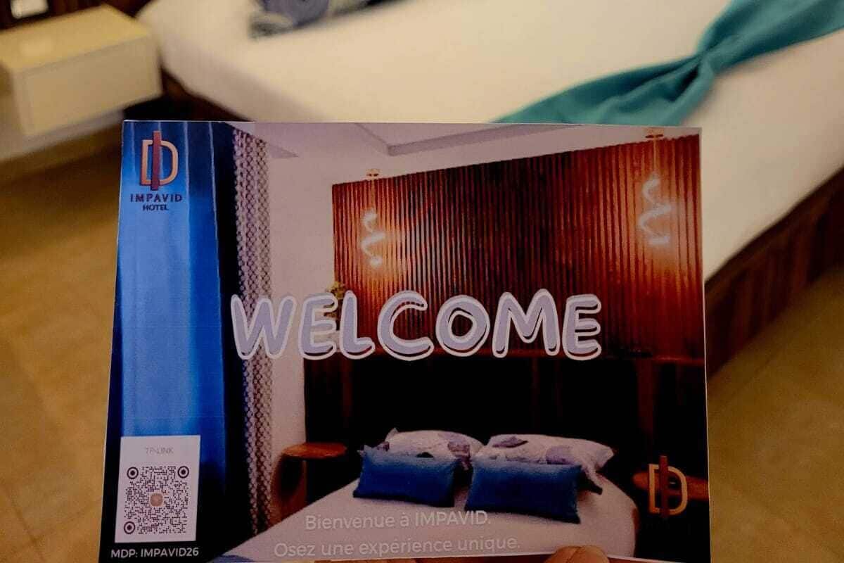 A hotel room with a bed, pillows, a bedside table, and a QR code on the wall.