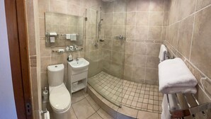 Un baño moderno con inodoro, lavabo y zona de ducha.