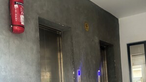En gang med to elevatordøre, en brandslukker og et skilt, der viser vejen til en garage.