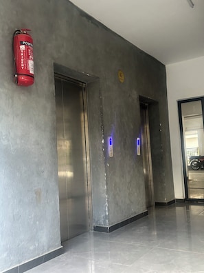 A hallway with two elevator doors, a fire extinguisher, and a sign indicating a garage. - Kindaruma Homes, 5 minutes away from yaya centre (Nairobi)