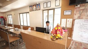 A hotel reception desk with a digital screen, a red Coca-Cola refrigerator, and a whiteboard with a welcome message.