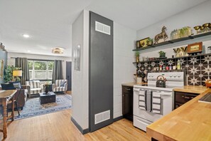A modern kitchen with a built-in oven and stove, a dining area with a wooden table and chairs, and a living room with a sofa and a coffee table. - Hilltop Manhattan Retreat Near K-State w/ Laundry (Manhattan)