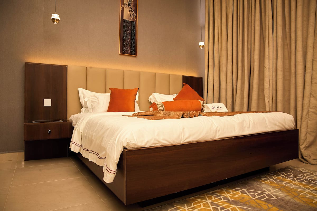 Una habitación de hotel con una cama grande, una mesita de noche, un espejo y un cabecero.