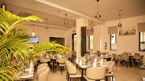 Comedor con mesas dispuestas para el servicio, sillas e iluminación colgante.