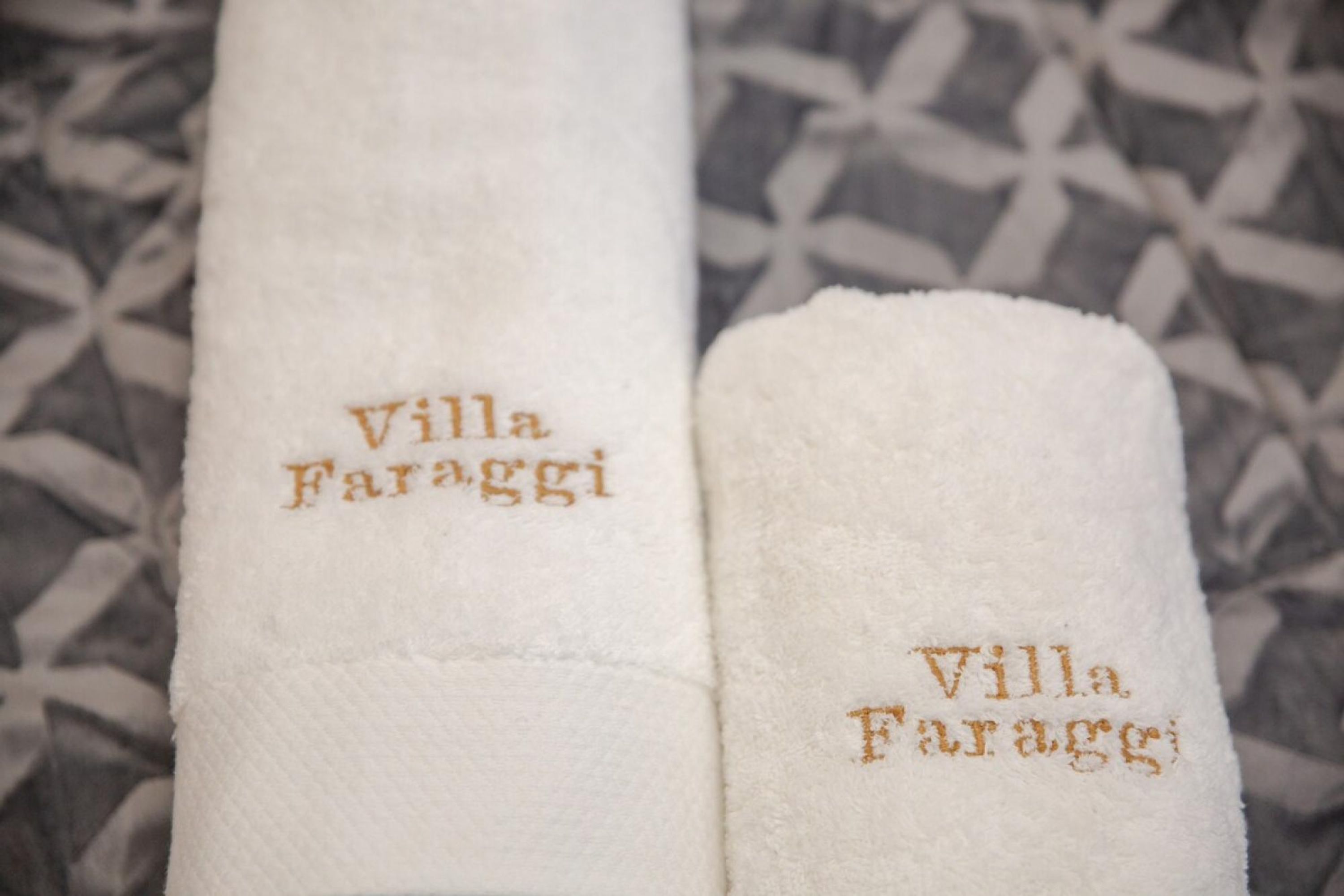 Two white towels with 'Villa Faraggi' embroidered in gold.