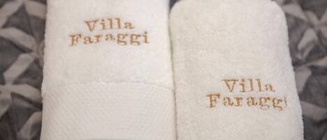 Two white towels with 'Villa Faraggi' embroidered in gold.