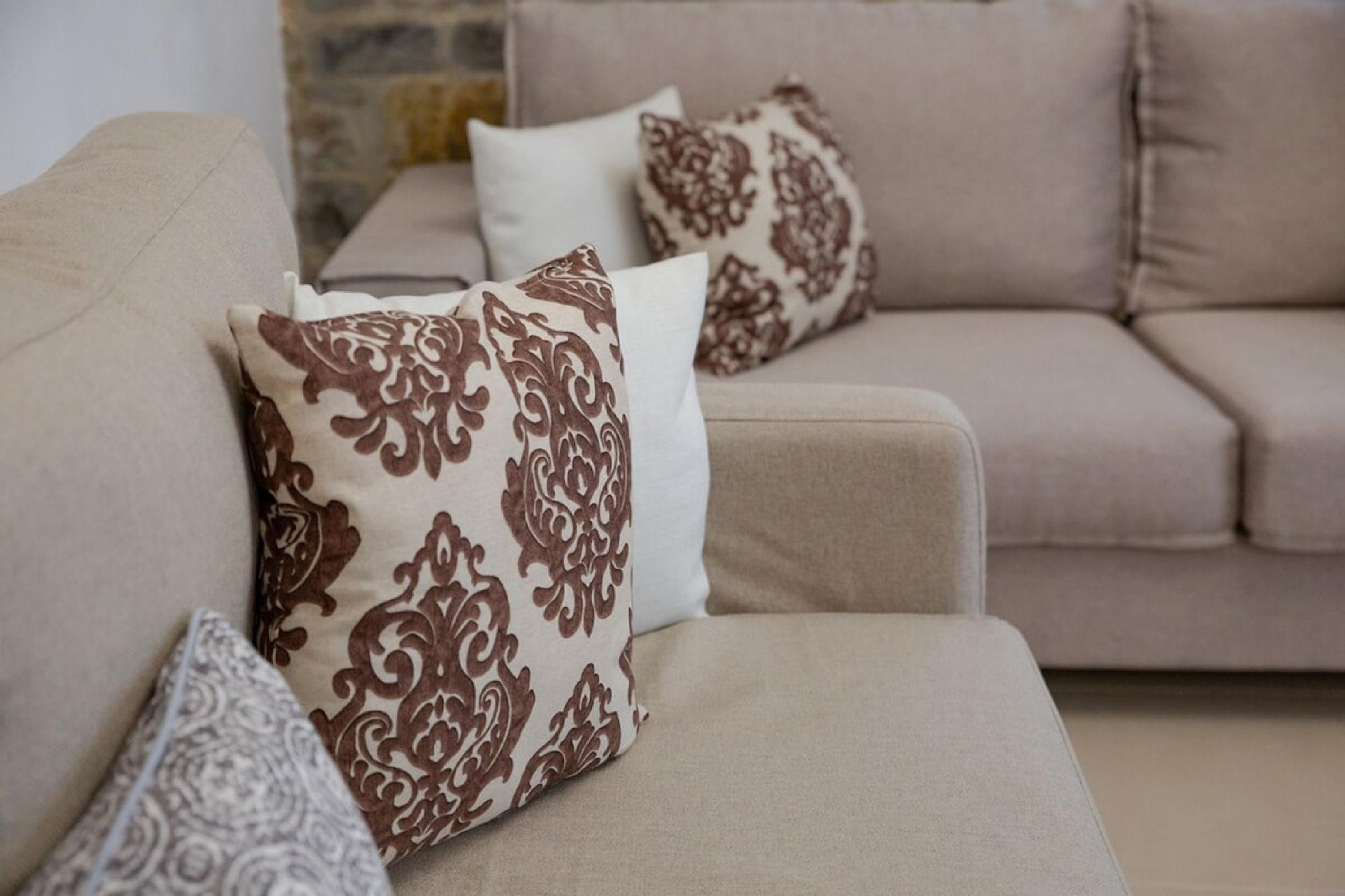 A beige sofa with patterned cushions.