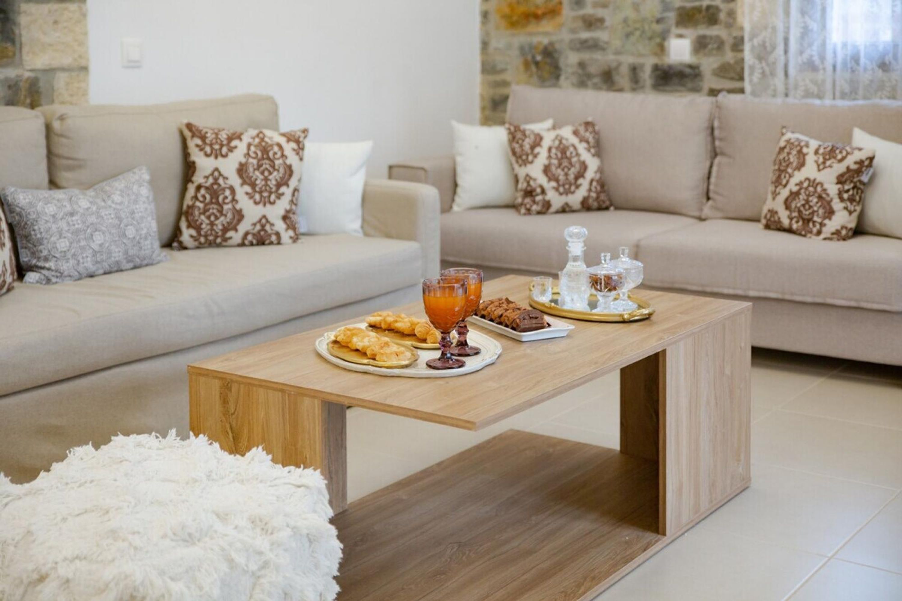 A living room with a wooden coffee table, a sofa, and a fluffy white rug.