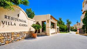 A villa entrance with a stone wall, a potted plant, and a clear blue sky. - Apartment 'Villa Gadea 7-1' with Shared Pool, Private Terrace and Wi-Fi (Villa Gadea urbanizacion)