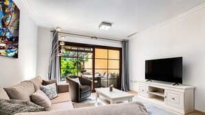 A modern living room with a sofa, TV, and a sliding glass door leading to an outdoor area. - Apartment 'Villa Gadea 7-1' with Shared Pool, Private Terrace and Wi-Fi (Villa Gadea urbanizacion)