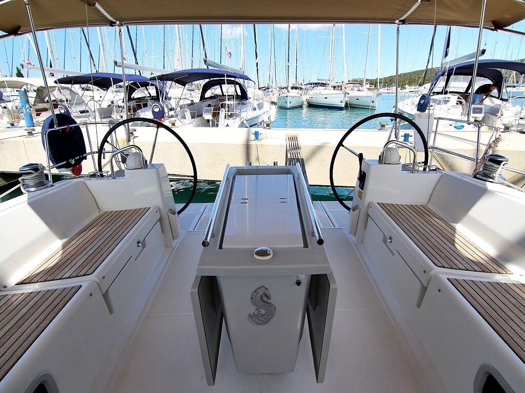 A boat deck with a steering wheel, control panel, and seating area.